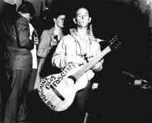 Woody Guthrie with "This Machine Kills Fascists" guitar